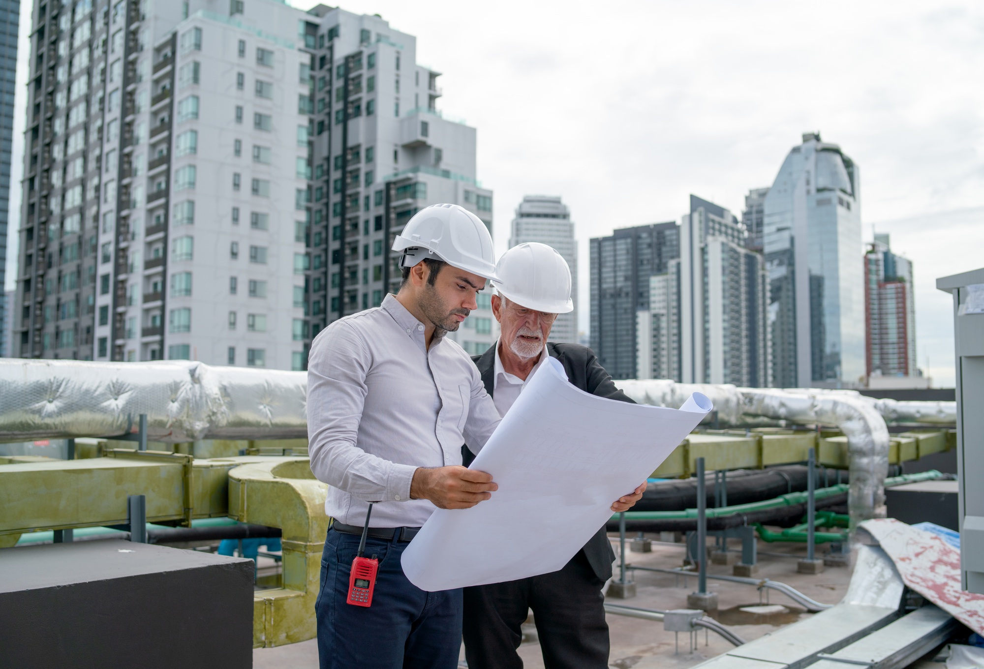 Young engineer hold drawing plan of building and discuss with senior coworker